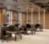 Moderni atviro plano biuro darbo erdvė su ergonomiškais stalais ir kėdėmis, medinių plokščių sienos ir kabančios pakabinamos lempos.