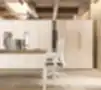 Aukštos baltos biuro spintos su paslėptomis rankenomis, moderniame interjere šalia darbo stalų su kompiuteriais ir ergonominėmis kėdėmis.