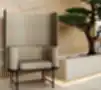 Šviesaus audinio fotelis su aukšta nugara, pastatytas prie medinių sienelių ir bonsai medžio japandi stiliaus interjere.
