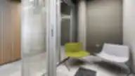 „Luminor“ biuro poilsio kampelis su žaliu ir baltu krėslais, mažu juodu staliuku ir dekoratyviniu augalu.