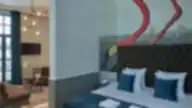 Prabangus viešbučio kambarys su flamingo piešiniu, dvigule lova ir poilsio zona.