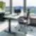 Citadele privatus biuras su reguliuojamo aukščio tamsaus medžio stalu, ergonomiška juoda tinklelio sukamoji kėde, žema juoda spintele po panoraminiais langais su vaizdu į upę ir miesto panoramą bei aukšta vazonine gyvyne.