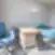 Nordclinic konsultacijų kabinetas Kaune su lenktu mediniu stalu, mėlynomis kėdėmis ir stovinčiu šviestuvu šviesioje patalpoje.
