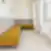 Rail holding poilsio zona su kampine moduline sofa pilkos ir garstyčių geltonumo spalvų, prie langų, baltos sienos ir sieniniai prožektoriai.