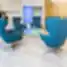 Moderni Nordclinic klinikos laukiamoji erdvė su ryškiai mėlynomis kėdėmis, stiklo staliuku ir šiuolaikiniu interjeru.