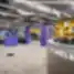 Plati moderni WORKLAND | VILNIUS, BURĖS biuro erdvė su ryškiai violetiniais stulpais, geltonomis lentynomis, pilku kilimu ir aptarnavimo balkonu prie įėjimo.