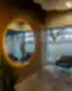 Modernus ir jaukus Neries odontologijos klinikos laukiamasis su medinėmis sienomis, apvaliu veidrodžiu, šviesos linijomis, pilkomis kėdėmis bei stikliniais staleliais.