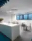 Moderni „New Crush“ biuro poilsio zona su balta virtuvės sala, LED žiediniu šviestuvu, mėlynomis grindimis ir stalo zona su kėdėmis