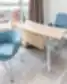 Modernus Nordclinic gydytojo kabinetas Kaune su mėlynomis kėdėmis, lenktu mediniu stalu ir miesto panorama pro langą.