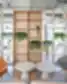 SHED Co-living Vilnius poilsio erdvė su moderniomis kėdėmis, apvaliais staliukais, medinėmis lentynomis ir kambariniais augalais.