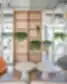 SHED Co-living Vilnius poilsio erdvė su moderniomis kėdėmis, apvaliais staliukais, medinėmis lentynomis ir kambariniais augalais.