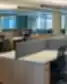 Moderni „Realco“ atvira biuro erdvė su darbo vietomis, atskirtomis pilkos spalvos pertvaromis ir ergonominėmis kėdėmis.