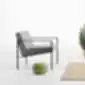 Šviesiai pilka apmušta kėdė su plonu juodu metalo rėmu, šalia moliūgo ir augalo – „Lund“ kėdė iš „Inclass“.