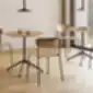 LEA kėdės šviesaus medžio kavinės aplinkoje su apvaliais stalais